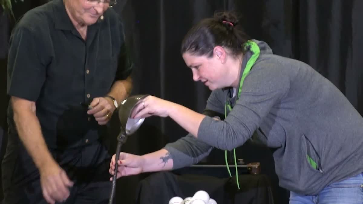 A guest on stage helping Jim Bodine pour from a magic pitcher